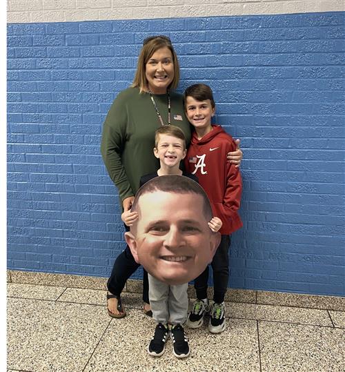 Teacher and sons with blown of picture of husband/father who is serving at the Pentagon